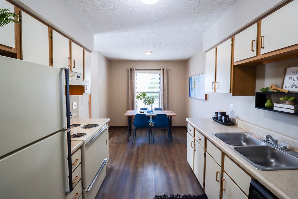 a kitchen and dining room with white appliances and wooden floors
