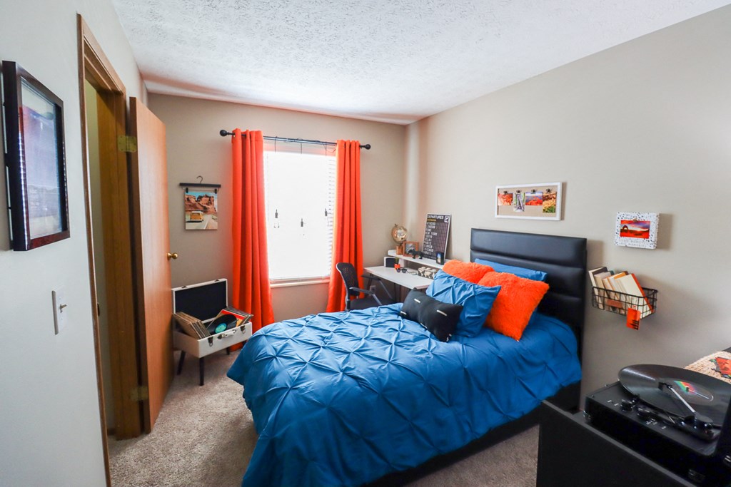 a bedroom with a blue bed and orange curtains
