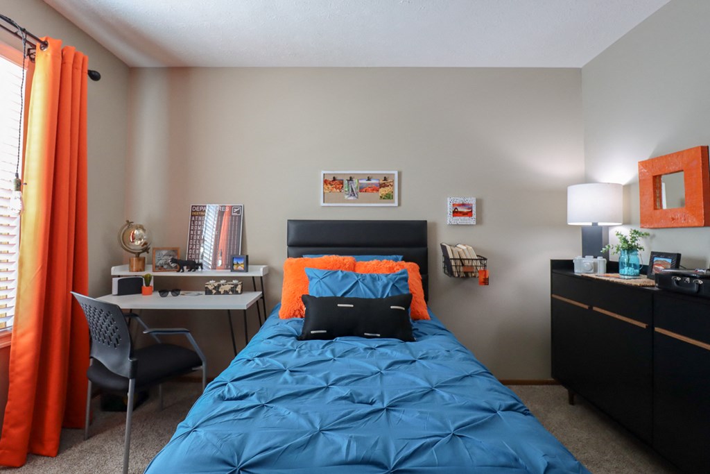 a bedroom with a bed and a desk with a dresser and