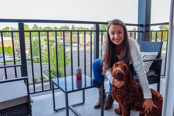 a woman sitting on a balcony with her dog