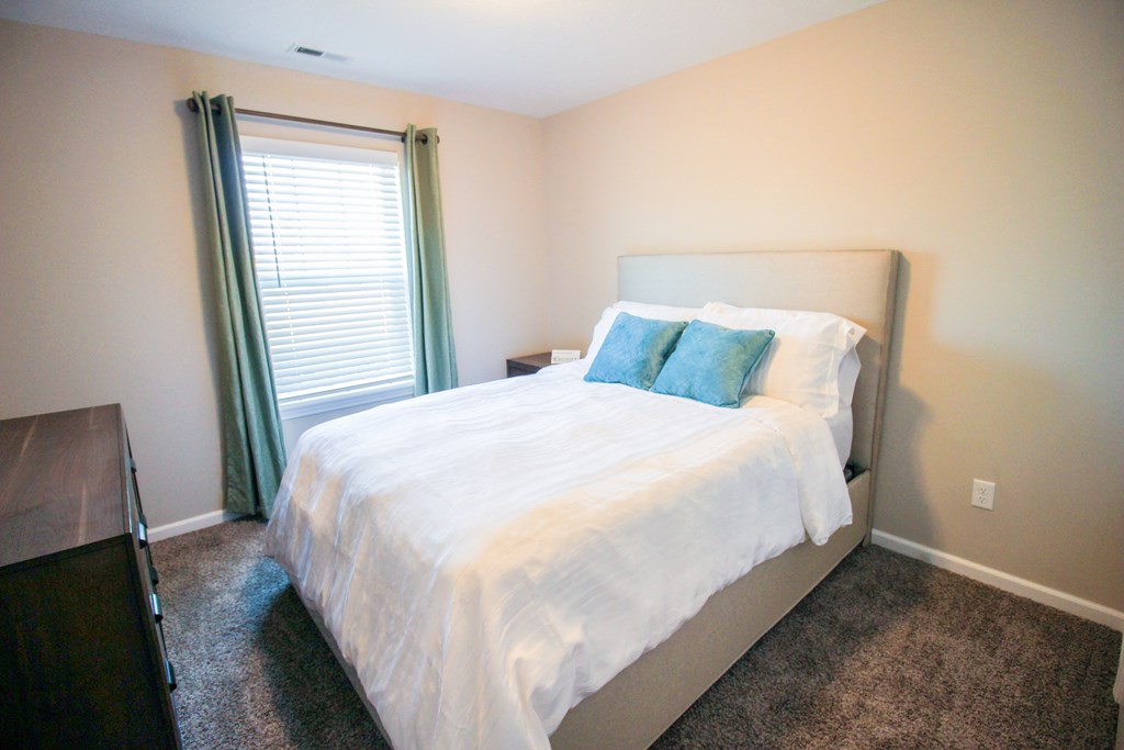 a bedroom with white bedding and green pillows