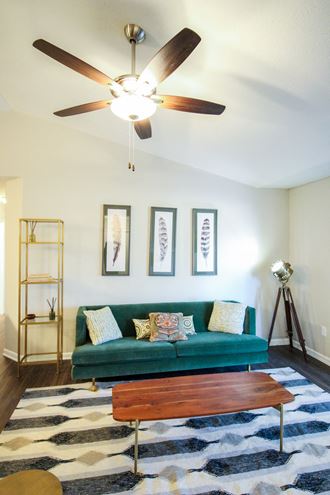 a living room with a green couch and a ceiling fan