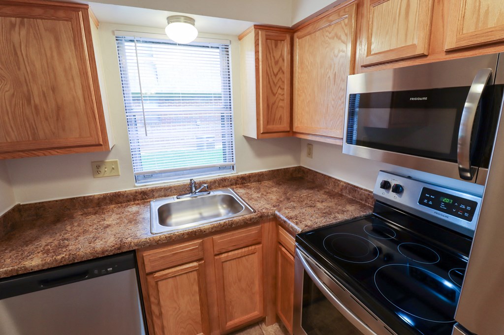 a kitchen with wood cabinets and black appliances and a granite counter top