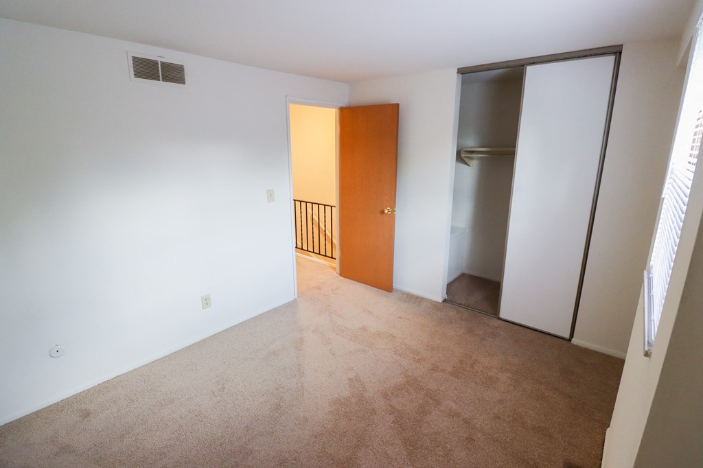 an empty living room with a door to a hallway and a closet