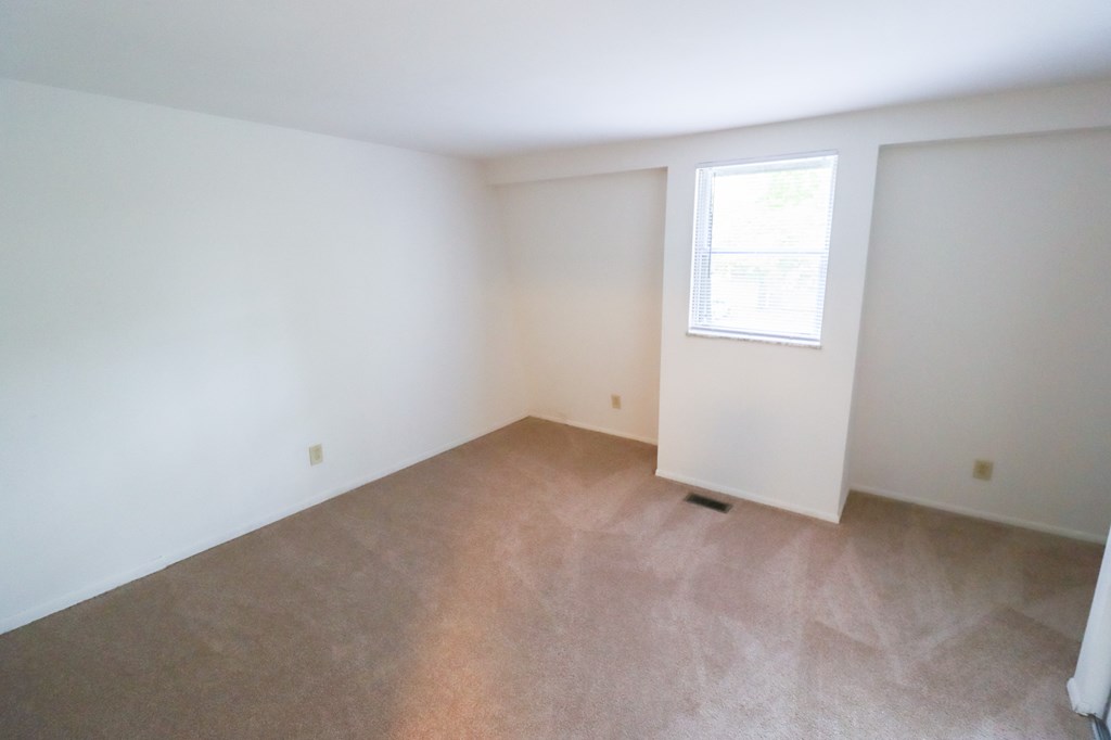 an empty room with a window and white walls