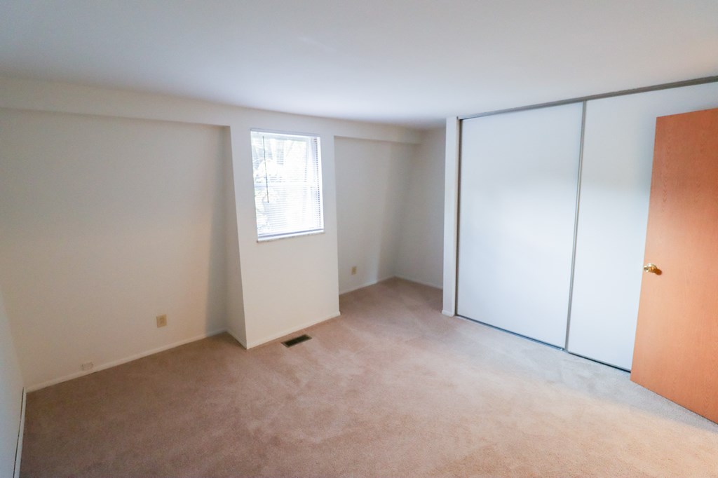 an empty room with white walls and a window and a closet