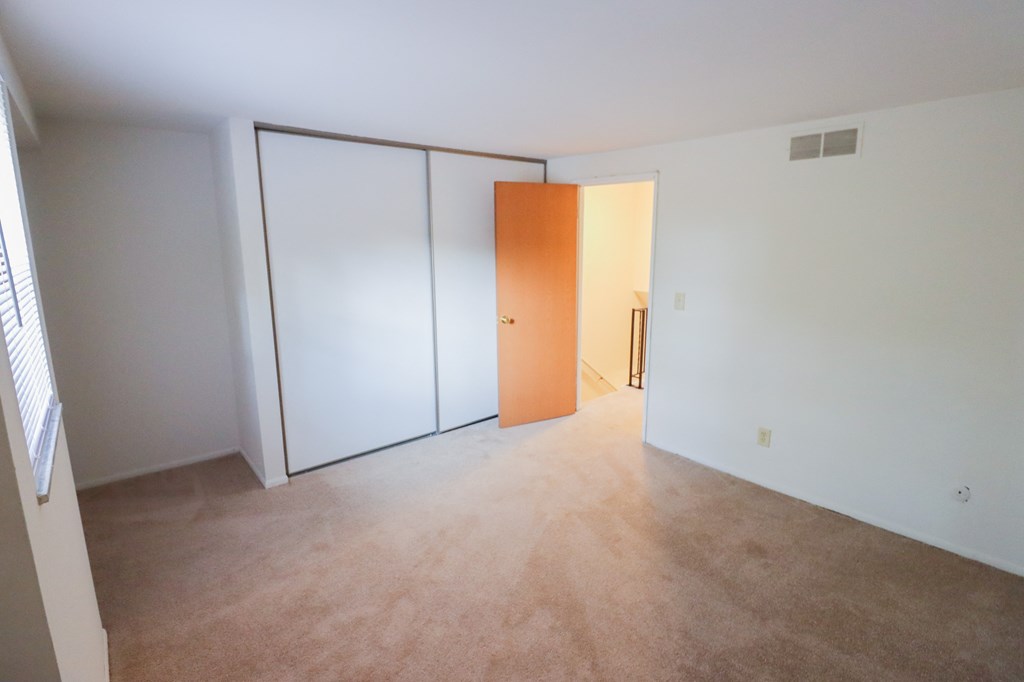an empty living room with white walls and a door to a closet
