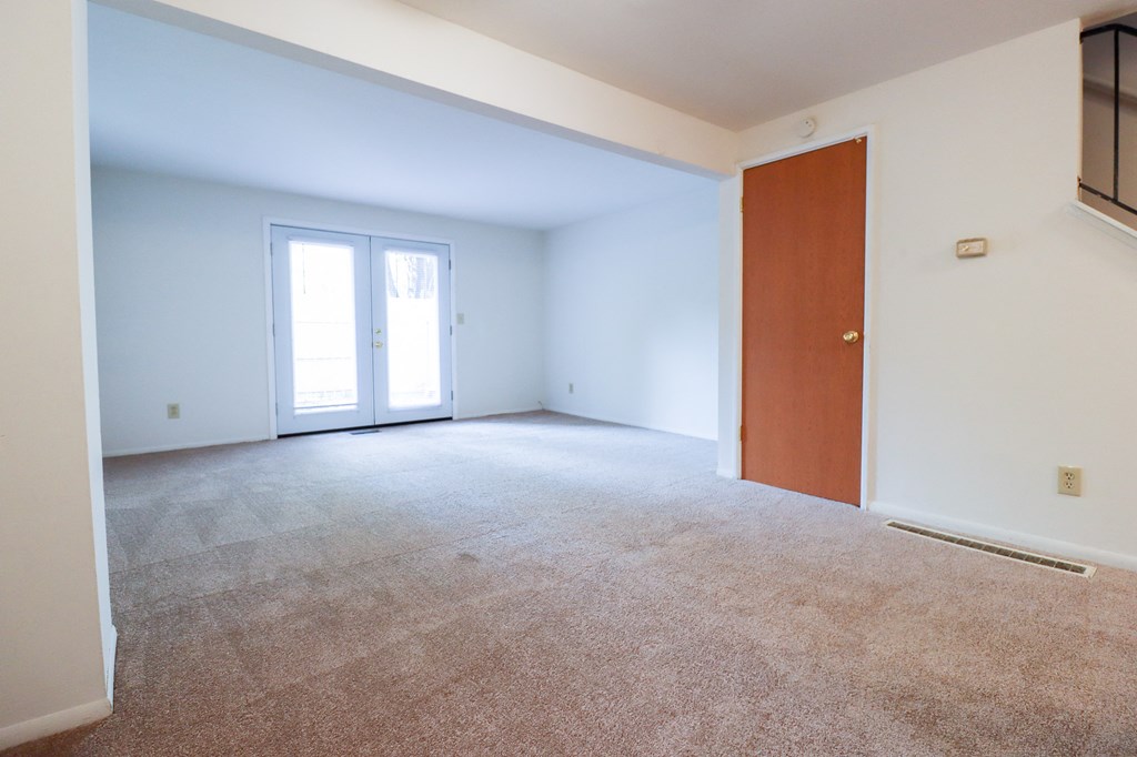 an empty living room with a door to a bedroom