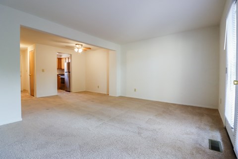 an empty living room with white walls and carpeting