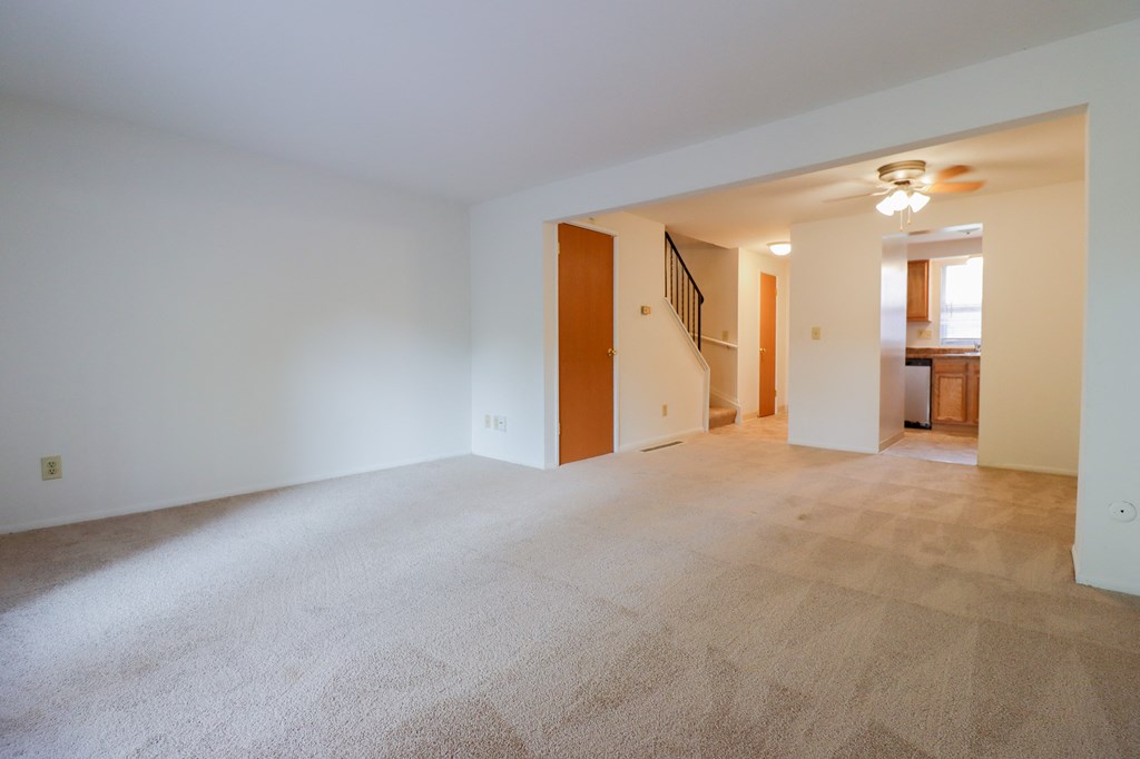a living room with carpet and a staircase in a house