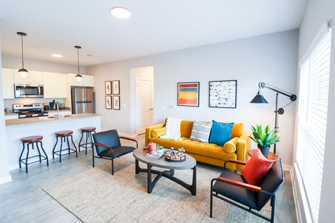 a living room with a yellow couch and a kitchen with a bar