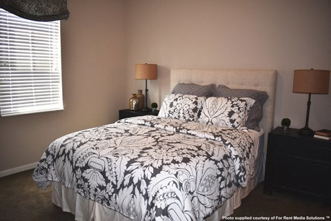a bedroom with a white and black bedspread and two lamps