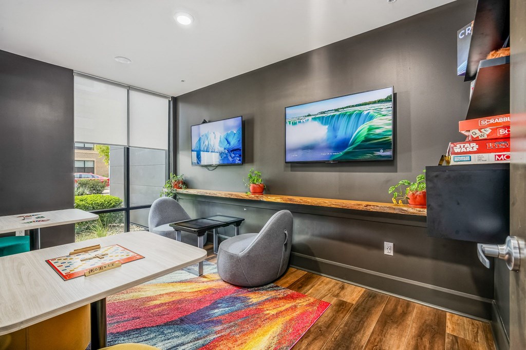 a conference room with a desk and two televisions on the wall
