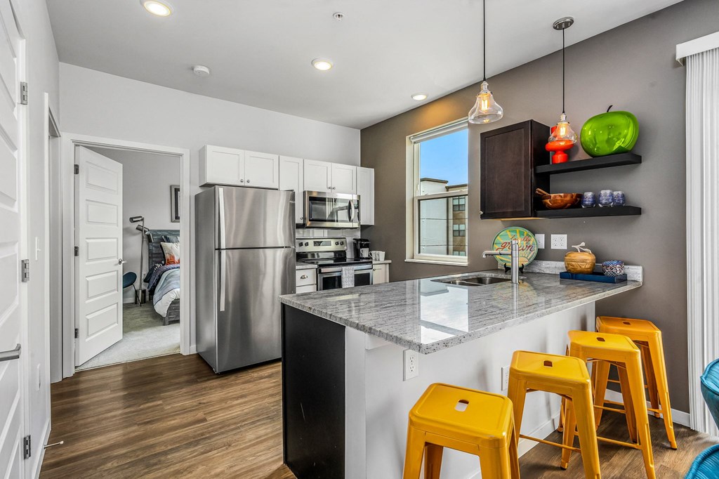 a kitchen with a counter with bar stools and a stainless steel refrigerator