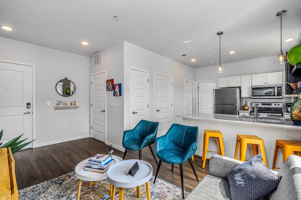 a living room with a kitchen with a bar and stools