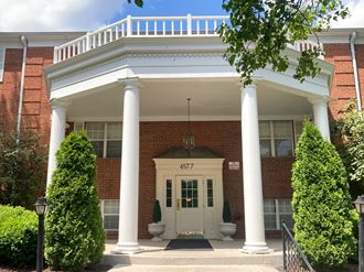 the front entrance of a brick building with a white porch