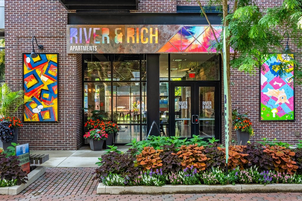a brick building with a large glass door and colorful paintings on the wall