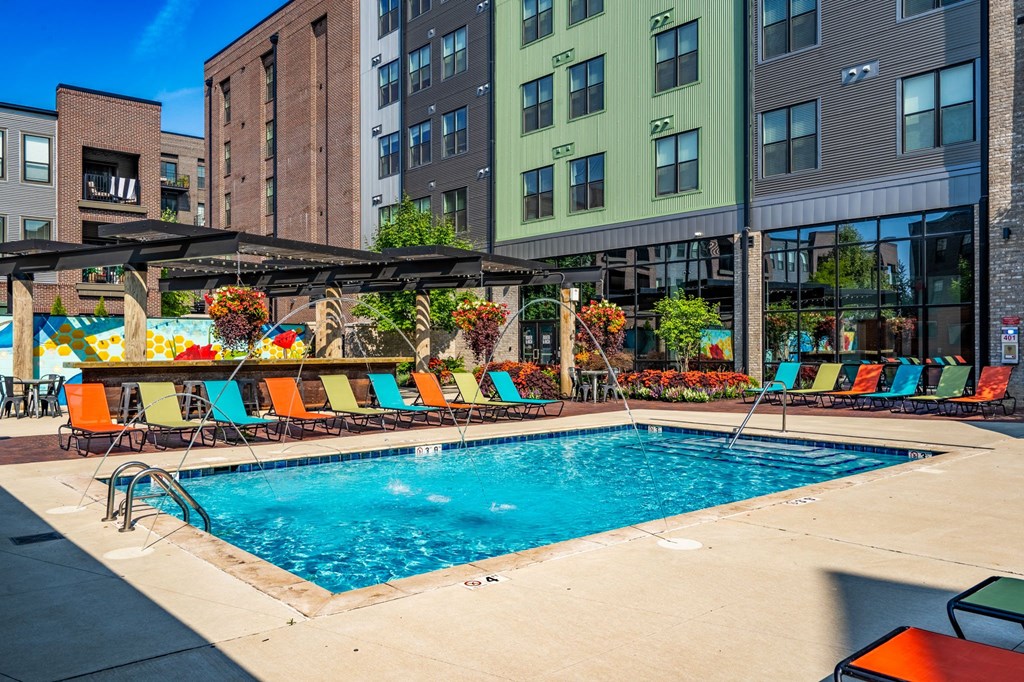 a swimming pool with lounge chairs and umbrellas in front of a building