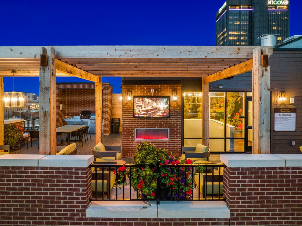 a patio with a fireplace and a wooden pergola at night