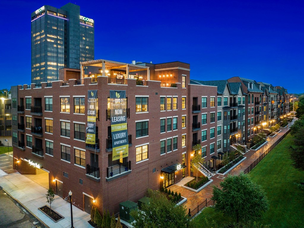 a large brick building with many windows and a grassy area in front of it