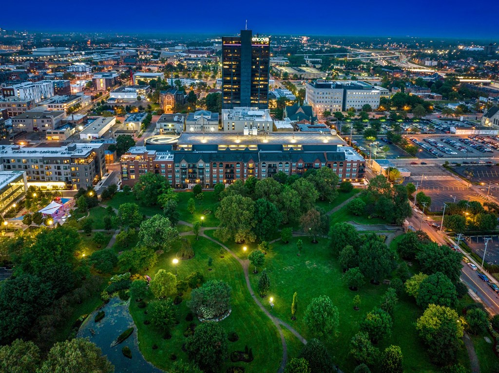 a cityscape at night with a park in the foreground and a tall building in the background