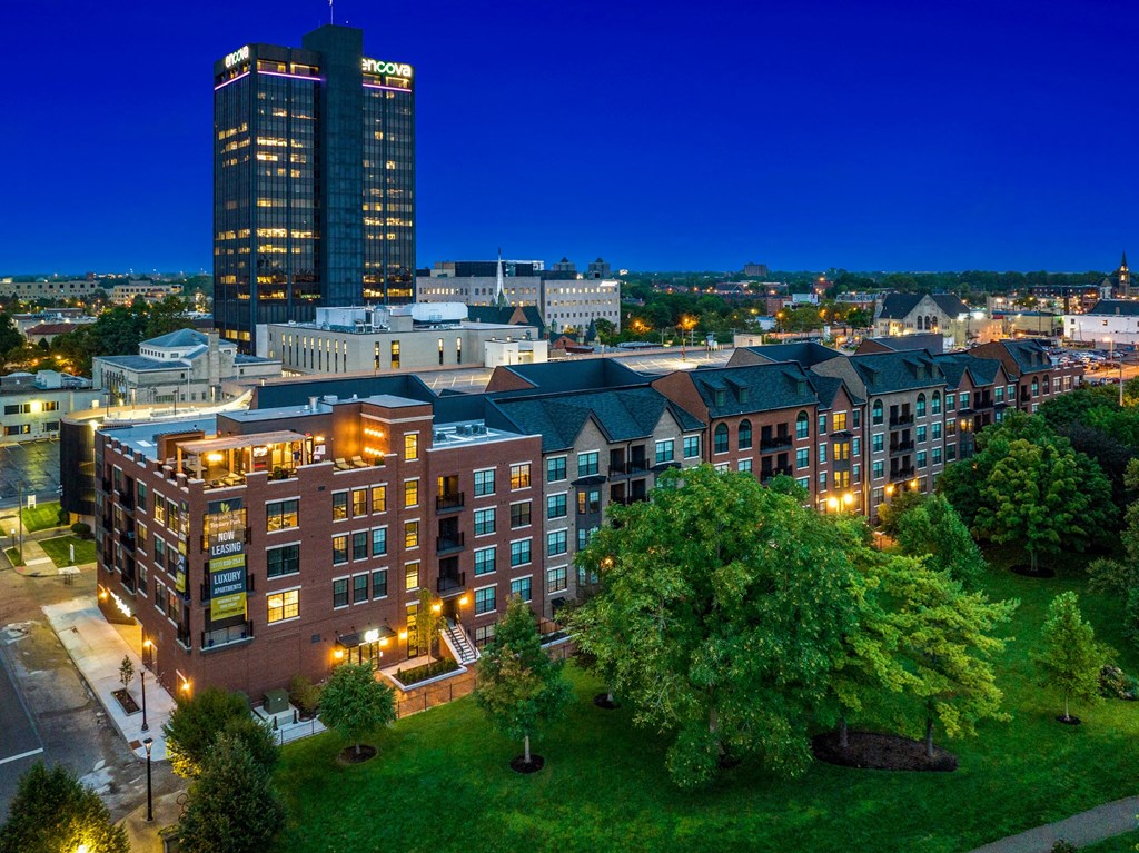 a large building with a green lawn and trees in front of it