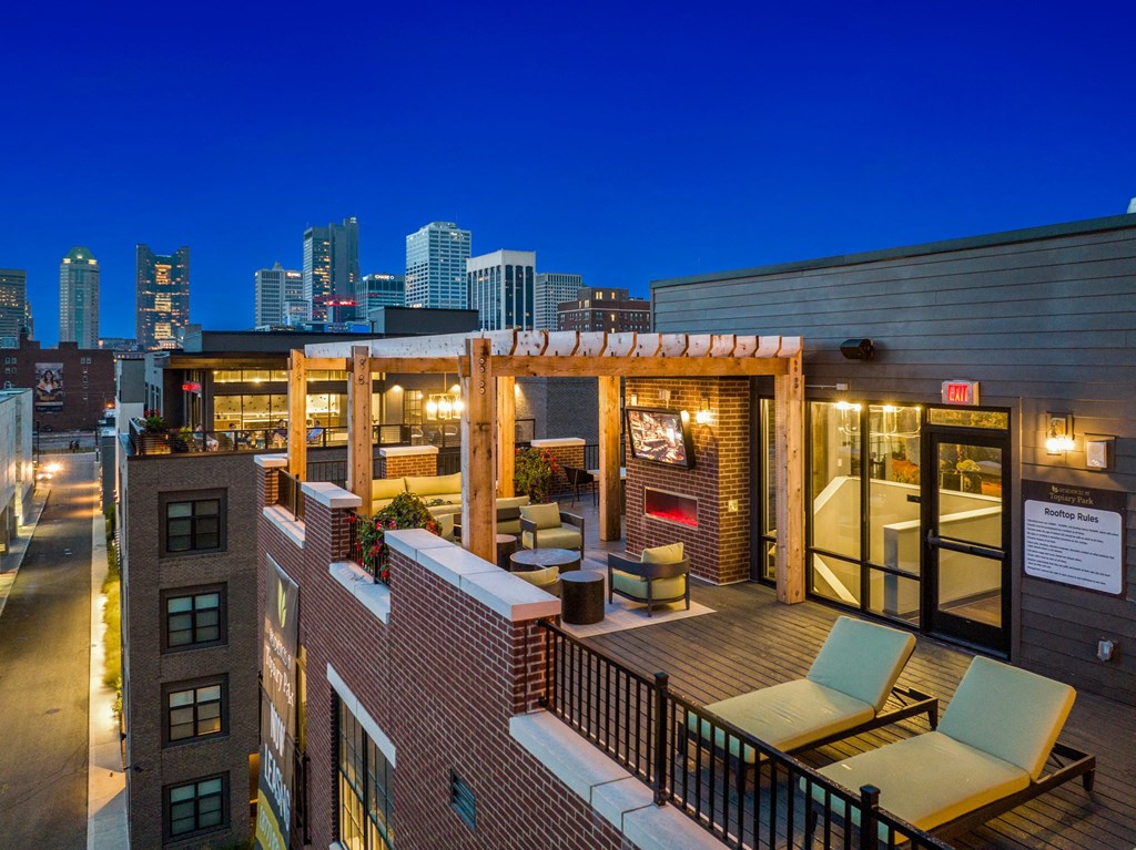 a rooftop deck with lounge chairs and a fireplace with a view of the minneapolis skyline