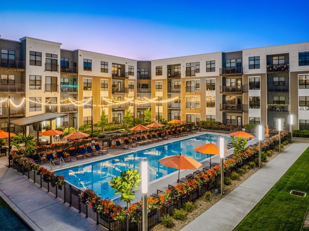 an apartment building with a swimming pool at dusk
