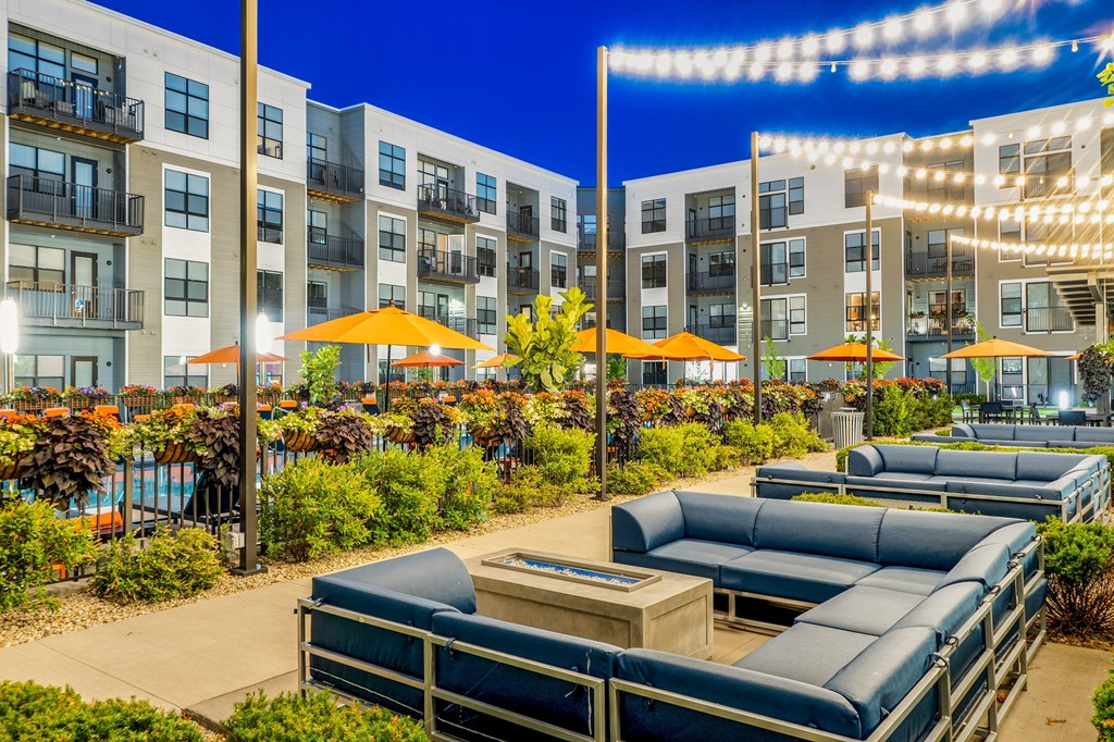 an outdoor patio with lounge chairs and umbrellas at night