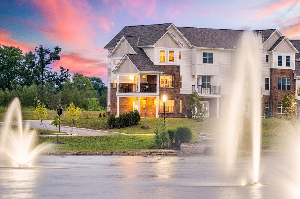 a fountain in front of a house at sunset