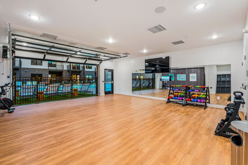 A spacious room with wooden floors and a variety of exercise equipment.