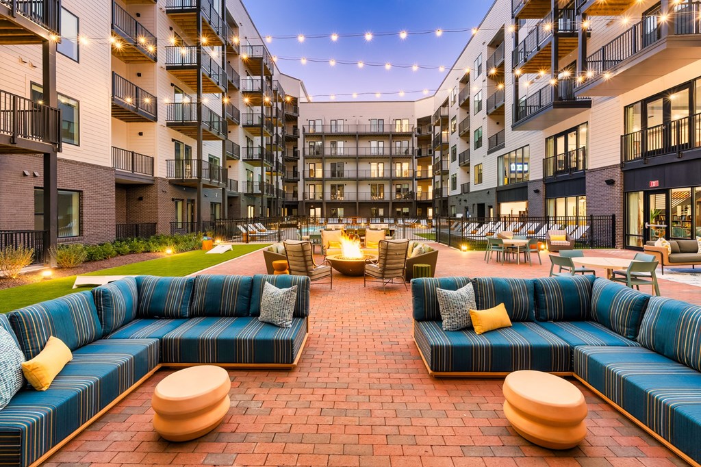 A large blue couch is in the middle of a courtyard surrounded by buildings.