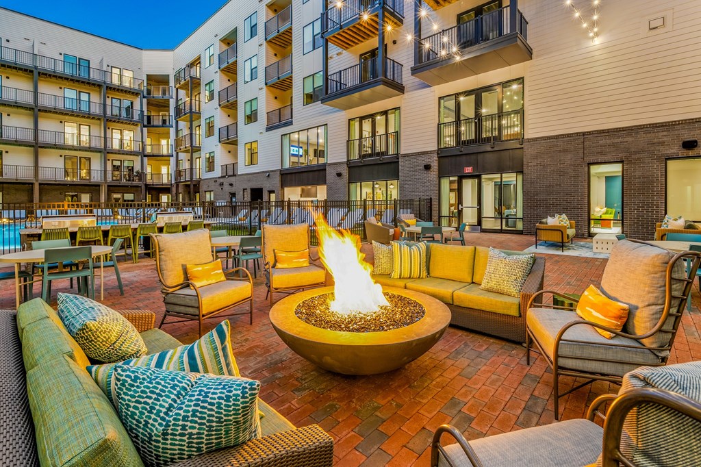 A patio with a fire pit and chairs.
