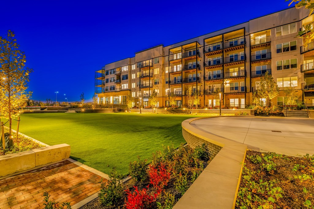 A modern apartment complex with a well-lit courtyard and landscaping.