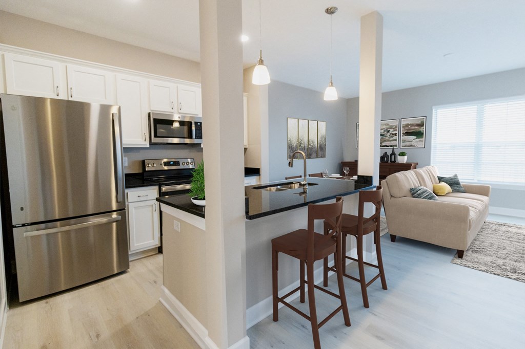 a kitchen and living room with stainless steel appliances and a bar with stools