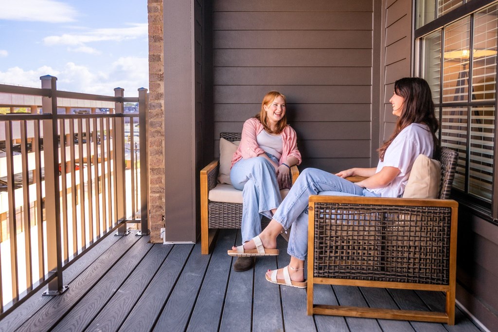 two women sitting on a porch talking