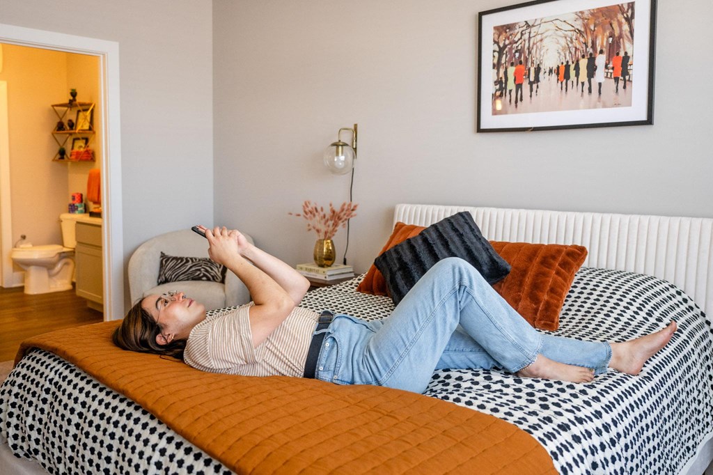 a woman laying on a bed with an orange blanket