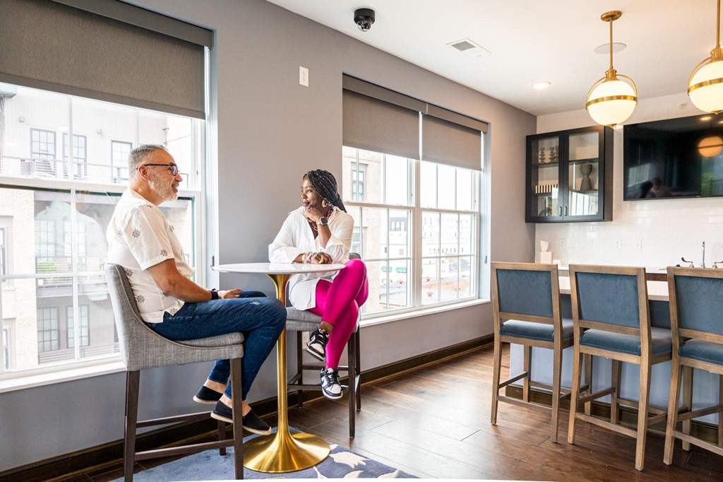 a man and a woman sit at a table in front of a window