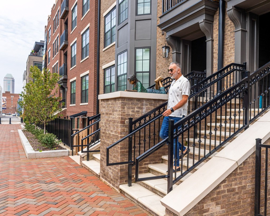a man in a white shirt and blue jeans walks down the stairs in front of a brick