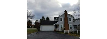 A house with a white fence and a brick chimney.