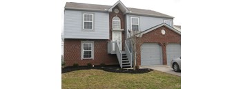 A house with a grey siding and a brick facade with a white door and windows.