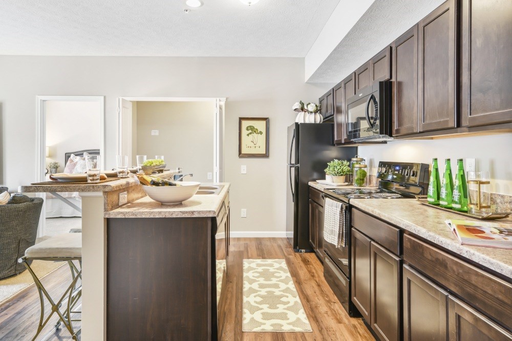 A kitchen with dark wood cabinets and a black refrigerator.