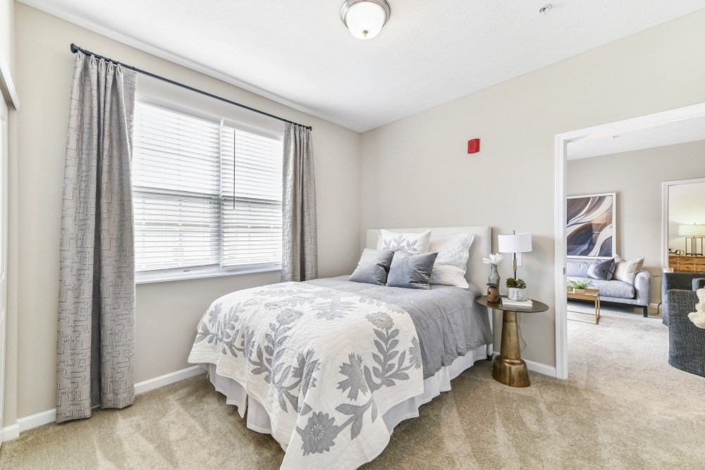 A bedroom with a bed, nightstand, and window.