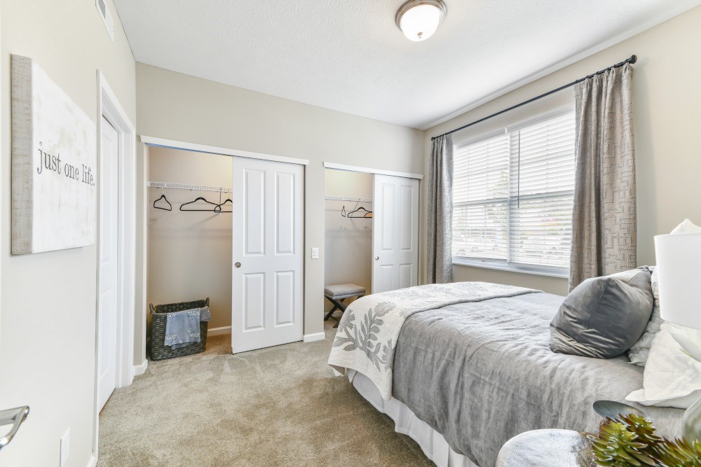 A bedroom with a bed, a window with curtains, and a wall hanging with the text "just one life".