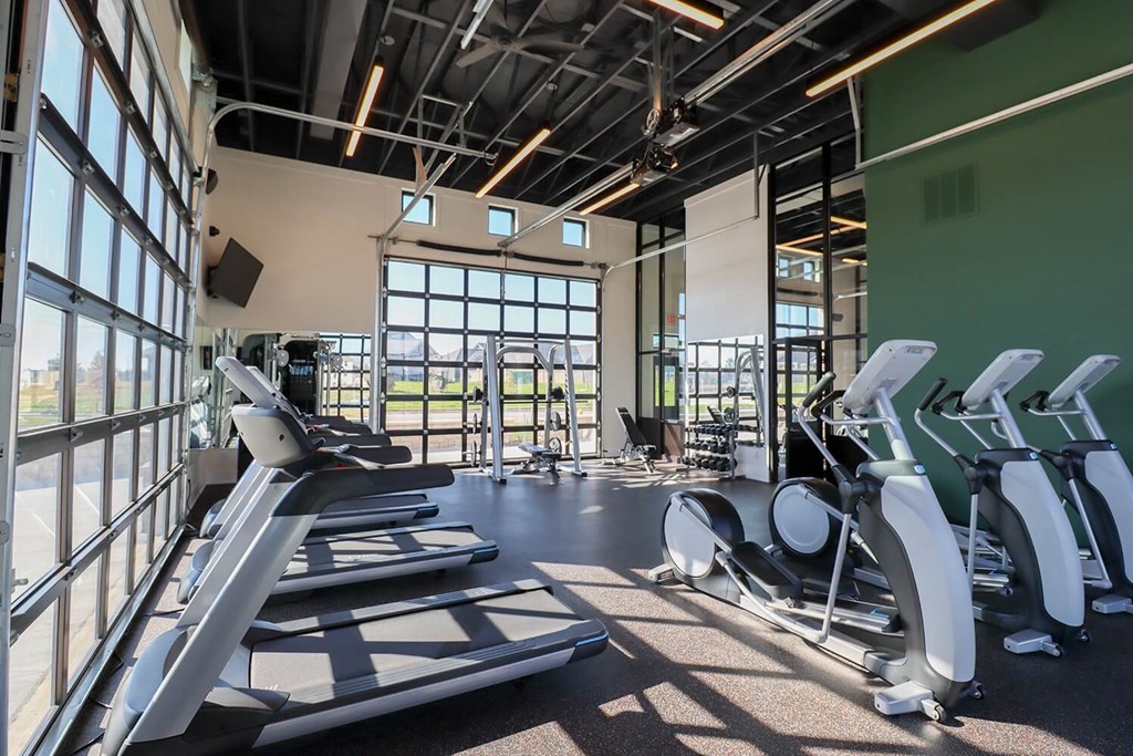 a gym with cardio equipment and windows in a building