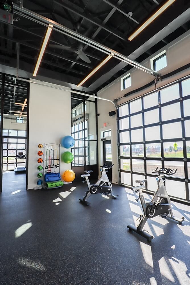 a workout room with exercise bikes and windows
