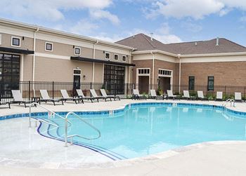 a swimming pool with chairs in front of a building