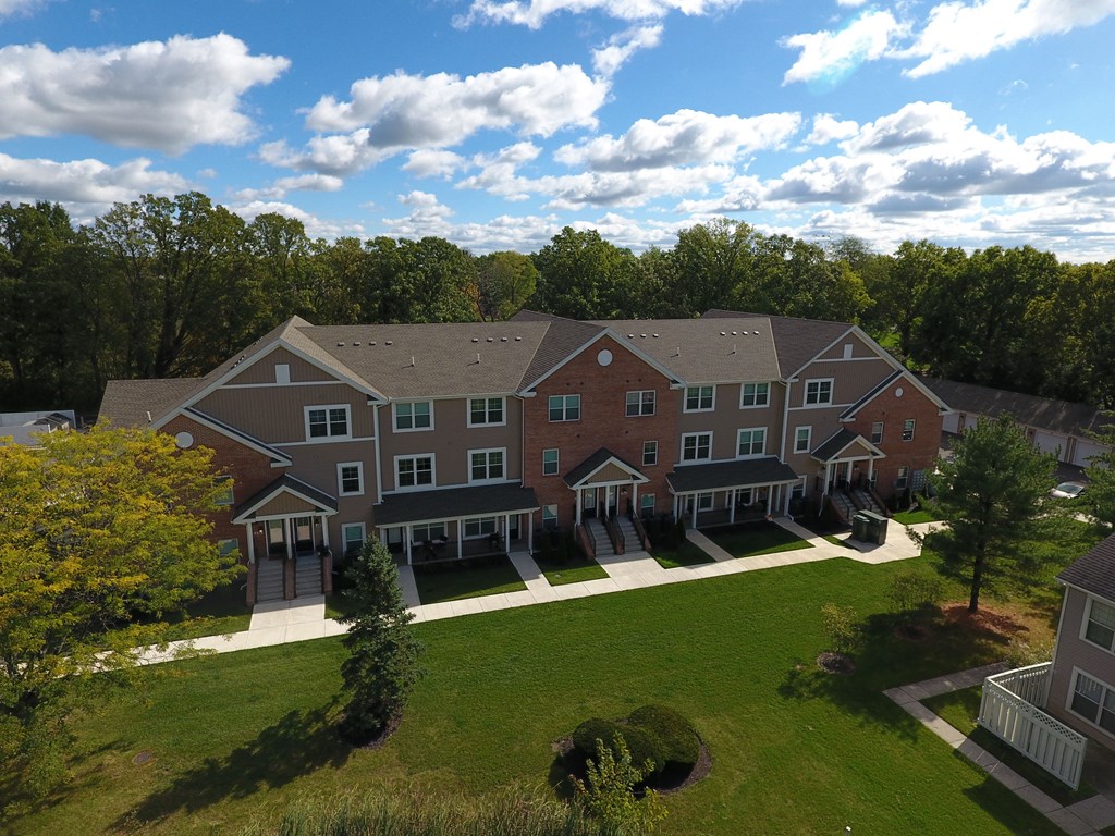 an aerial view of a large building with a green lawn and trees