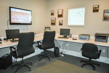 a computer room with three desks and three chairs and a monitor