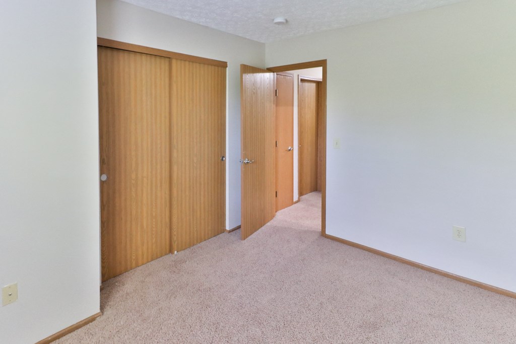 an empty room with two doors and a carpeted floor